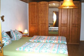 A bedroom with a bed, pillows, a nightstand, a lamp, and a wardrobe. - Holiday home with 1 bedroom (Neureichenau)