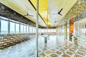 Un espacio interior amplio con piso estampado, ventanas grandes y ventiladores de techo.