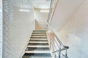 A staircase with a metal handrail, patterned walls, and a tiled floor. - Hotel O Shakti Inn (Jamshedpur)