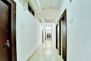 A corridor with doors on both sides, a tiled floor, and a ceiling with recessed lighting. - Hotel O Shakti Inn (Jamshedpur)