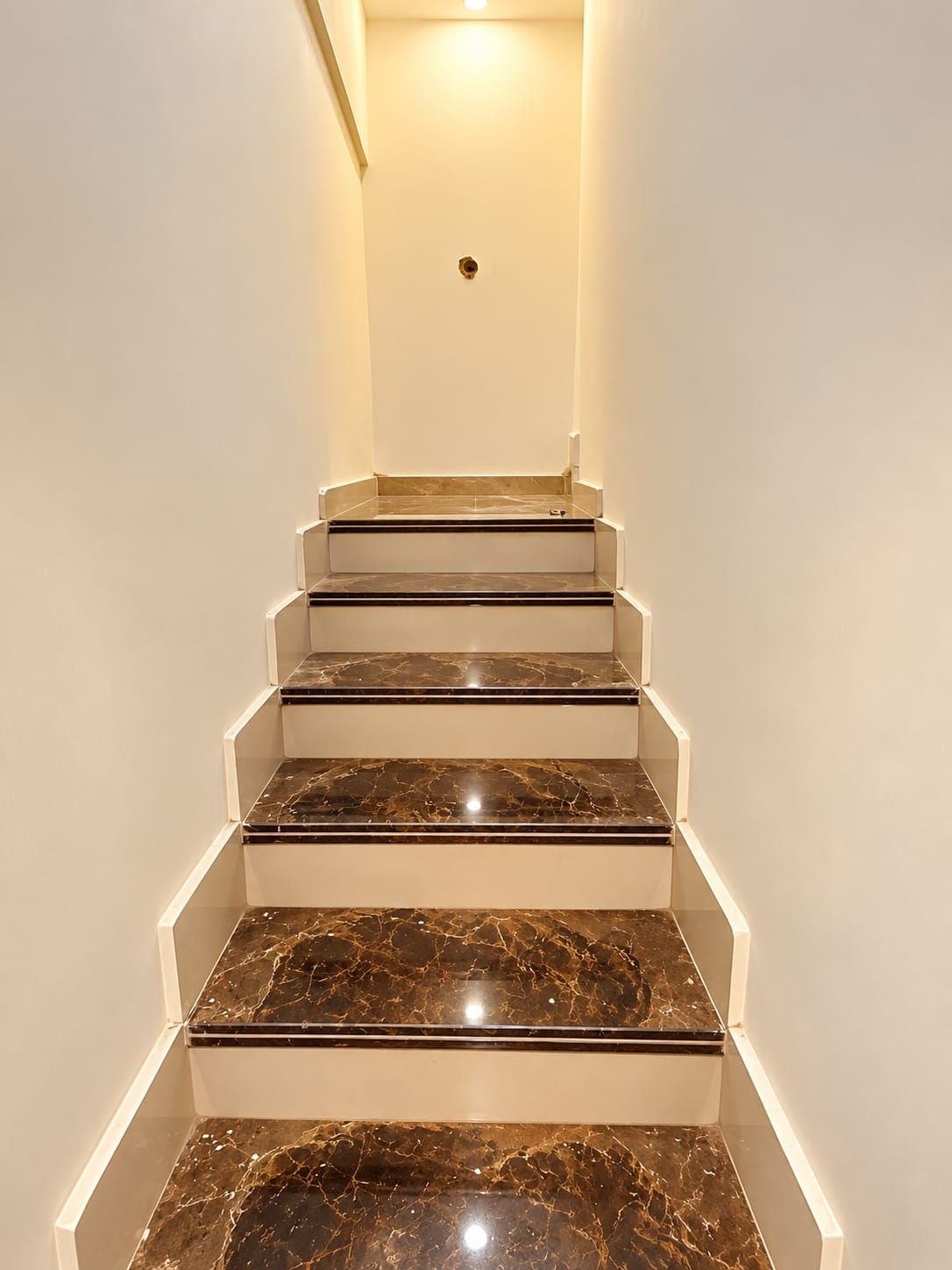 Una escalera con detalles de mármol y paredes blancas.