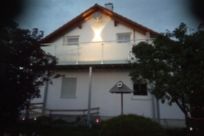 A two-story building with a balcony, a visible satellite dish, and a bench in the foreground. - Holiday in the Ostallgäu region (Lengenwang)