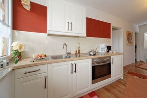 A kitchen with white cabinets, a stainless steel sink, and a built-in oven. - Tannenhof holiday and riding facility (Neukichen beim Heiligen Blut)