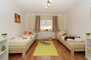 A room with two single beds, a window with curtains, a green rug, and a ceiling light fixture. - Tannenhof holiday and riding facility (Neukichen beim Heiligen Blut)