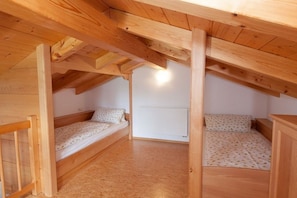 A small attic bedroom with two wooden bunk beds, a white radiator, and a sloped ceiling. - Country house Kreutzer "Beim Sima" (Rieden)