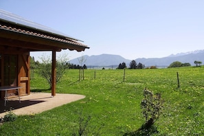 A wooden cabin with a patio, surrounded by a lush green field and mountains in the background. - Country house Kreutzer "Beim Sima" (Rieden)