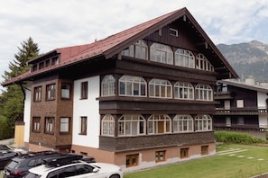 Ein mehrstöckiges Gebäude mit geneigtem Dach, großen Fenstern und einem Parkplatz davor.
