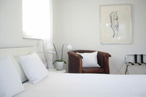 A bedroom with a bed, a chair, a potted plant, a framed artwork, and a radiator. - "Lake in view" in Hagnau on Lake Constance (Hagnau)