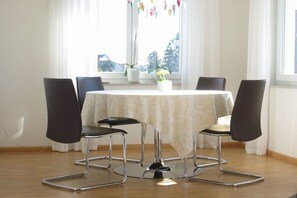 A dining area with a round table, four chairs, and a window with curtains. - "Lake in view" in Hagnau on Lake Constance (Hagnau)