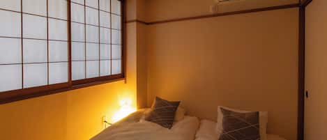Una habitación con una cama, una ventana con diseño de cuadrícula y un equipo de aire acondicionado.