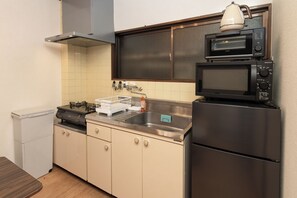 A compact kitchen with a stove, sink, microwave, and a refrigerator. - Ocean Namba (Osaka)