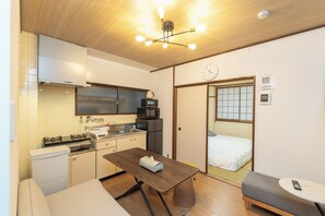 A compact kitchen with a gas stove, microwave, and a small refrigerator. - Ocean Namba (Osaka)