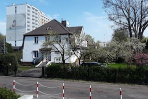 A two-story house with a white facade, a dark roof, and a visible staircase leading to the entrance. - Holiday apartment with 1 bedroom (Kolobrzeg)