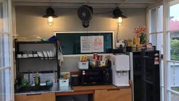 A small, enclosed food service area with a counter, storage cabinets, and a fan.