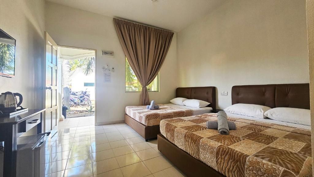 Habitación de hotel con dos camas, un escritorio y vistas al exterior.