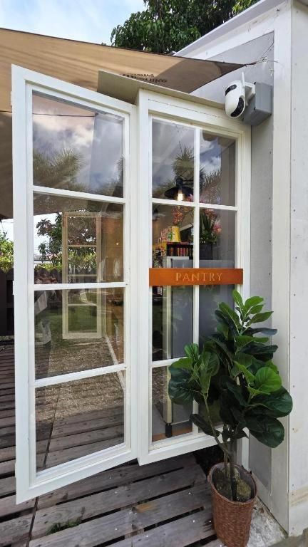 Una puerta corrediza de vidrio con un letrero que dice 'PANTRY', una planta en maceta y una terraza de madera.