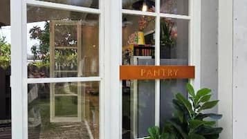 Una puerta corrediza de vidrio con un letrero que dice 'PANTRY', una planta en maceta y una terraza de madera.