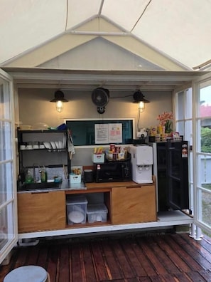 A small, enclosed food service area with a counter, storage cabinets, and a fan. - CASA YUSIKA (Langkawi)