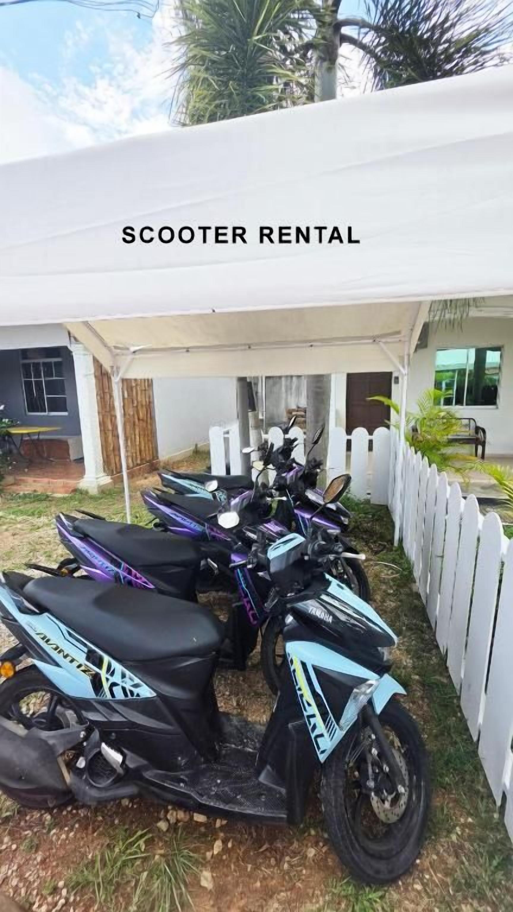 A scooter rental area with multiple scooters under a white canopy.