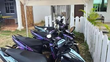 A scooter rental area with multiple scooters under a white canopy.