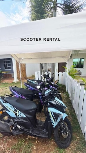 A scooter rental area with multiple scooters under a white canopy. - CASA YUSIKA (Langkawi)