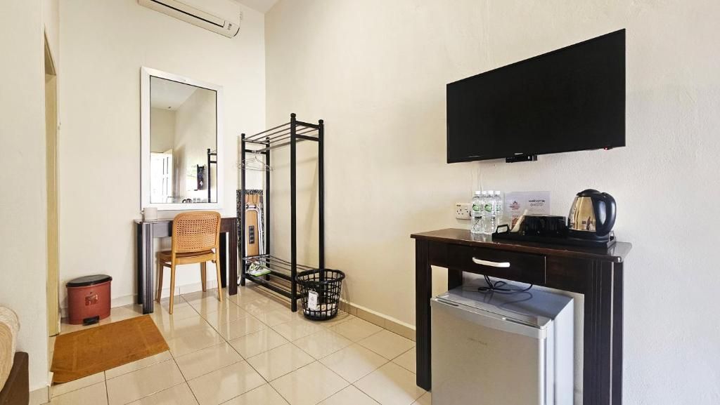 Habitación de hotel con cama, escritorio, televisor de pantalla plana, cafetera y refrigerador pequeño.