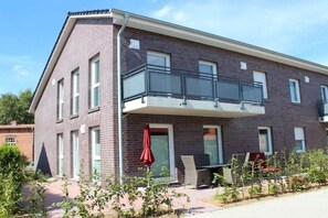 Ein zweistöckiges Gebäude mit Balkon, rotem Sonnenschirm und Ziegelwand.