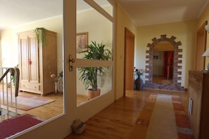 A hallway with wooden flooring, a potted plant, a cabinet, and a door leading to another room. - Holiday apartment with 2 bedrooms (St. Wendel-Winterbach)
