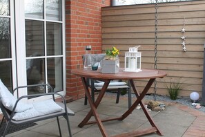 Eine Terrasse mit einem runden Tisch, einem Stuhl und einer hängenden Leuchte.