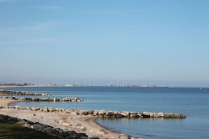 A coastal landscape with a rocky shoreline, calm water, and distant buildings. - Holiday apartment with 2 bedrooms (Schönhagen)