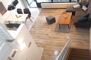 A modern living room with a sofa, a coffee table, and a dining area with chairs and a table. - Holiday apartment with 2 bedrooms (Kellenhusen)