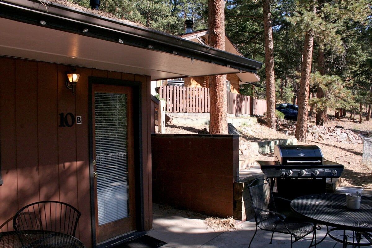A covered outdoor area with a grill, a table, and chairs.