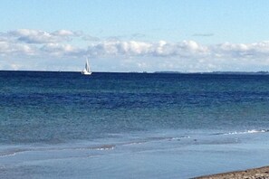 A coastal scene with a clear sky and a sailboat on the water. - Holiday home House 105 (Damp)