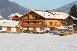 Un chalet en bois doté de plusieurs balcons, d’un toit enneigé et surplombant un paysage montagneux.