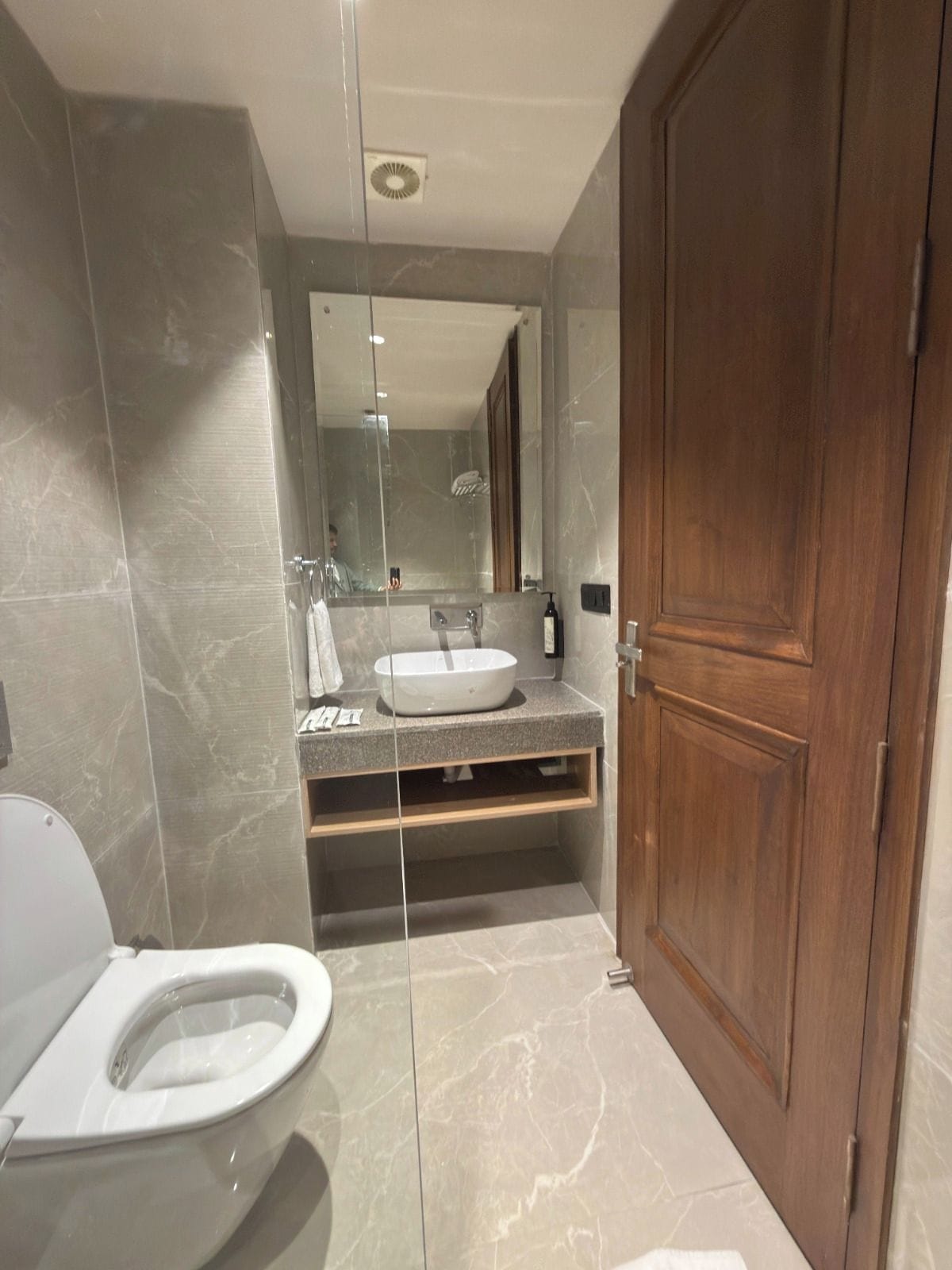 Un baño con inodoro, lavamanos y espejo.