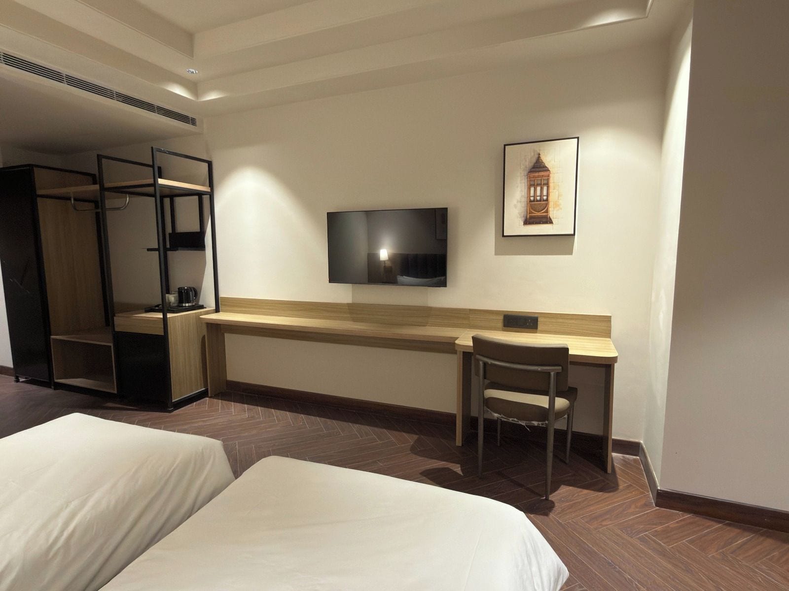 Una habitación de hotel con una cama, un escritorio, una silla, un televisor y un armario.