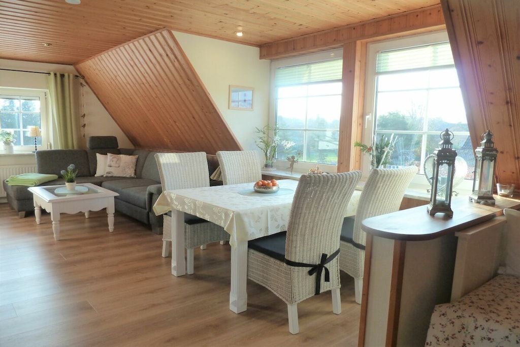 A cozy room with a dining table, chairs, a sofa, and a window with a view.