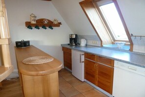 Eine Küche mit Holzschränken, einer Arbeitsplatte, einer Kaffeemaschine und einem kleinen Kühlschrank.
