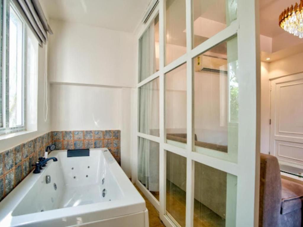 A bathroom with a large bathtub, a window, and a door leading to another room.