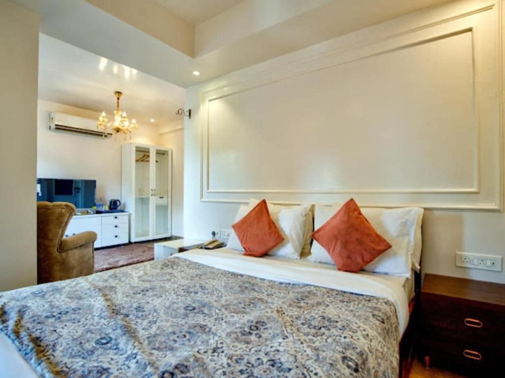 Una habitación de hotel con una cama grande, un armario, un escritorio y un espejo.
