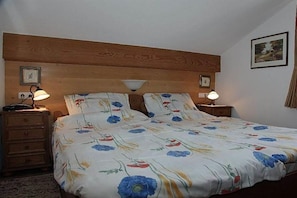 A bedroom with a wooden headboard, two bedside lamps, a floral bedspread, and a framed picture on the wall. - Holiday apartment with 2 bedrooms (Burgberg)