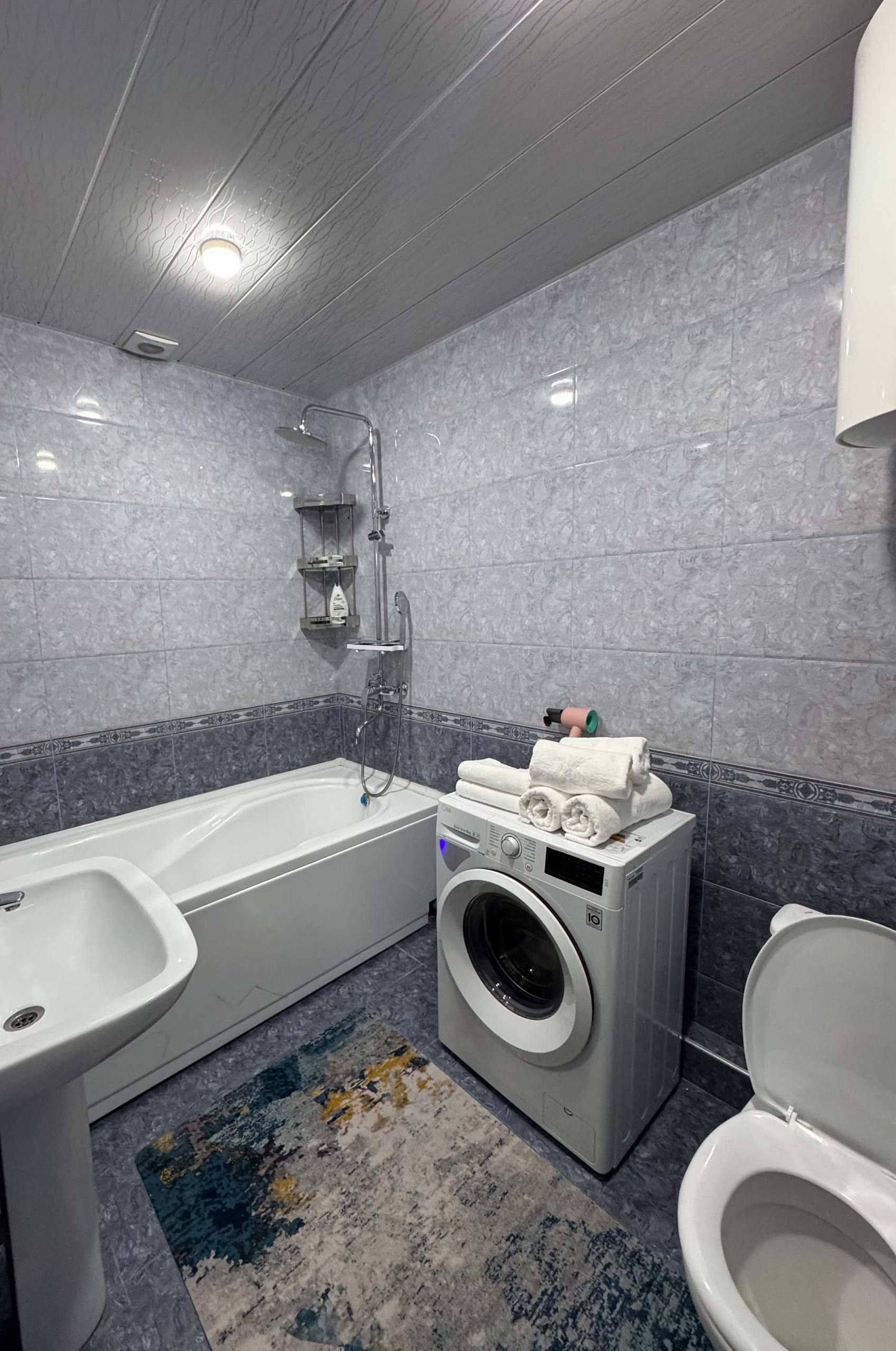 Ein modernes Badezimmer mit Badewanne, Waschmaschine und Toilette.