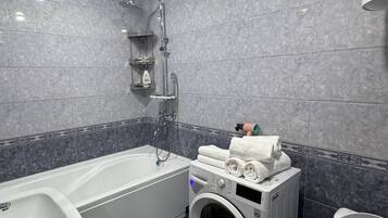 Ein modernes Badezimmer mit Badewanne, Waschmaschine und Toilette.