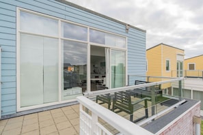 En boligbygning med balkon, store skydedøre og et synligt køkkenområde.
