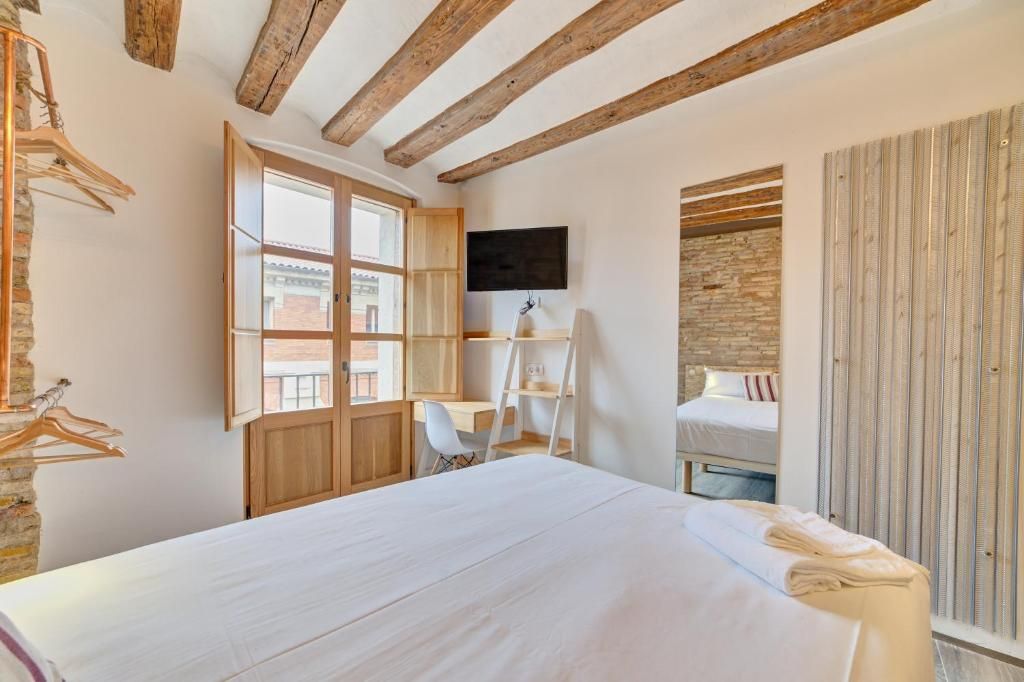 A bedroom with a bed, a desk, a chair, a TV, and a wardrobe.