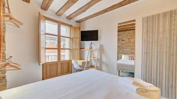 A bedroom with a bed, a desk, a chair, a TV, and a wardrobe.