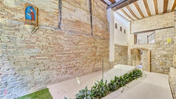 A stone interior with a wooden ceiling, a staircase, and a wall-mounted light fixture.