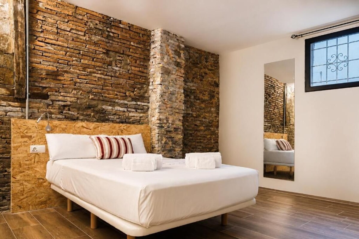 Un dormitorio con una cama grande, una pared de ladrillo y una ventana.