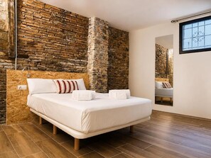 Un dormitorio con una cama grande, una pared de ladrillo y una ventana.