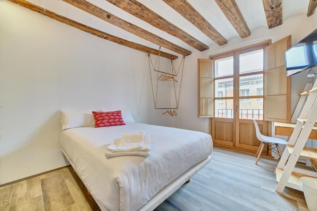 Ein Schlafzimmer mit einem Bett, einem Holzstuhl, einem Schreibtisch und einem Fenster mit Blick.